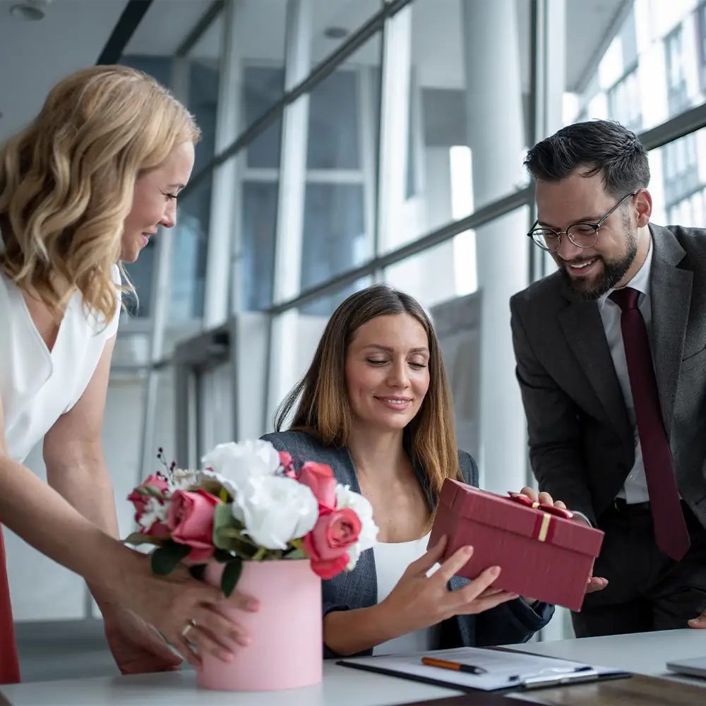 Das Business-Team überreicht einem Kollegen im Büro Geschenke und Blumen.